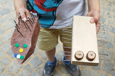 Ein Kind präsentiert seinen gebauten Igel und Tausentfüßler aus Holz.
