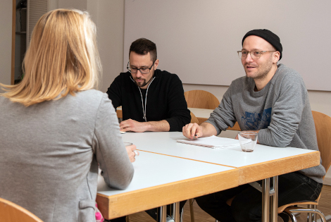 Drei Personen sitzen am Tische für eine Beratungsgespräch