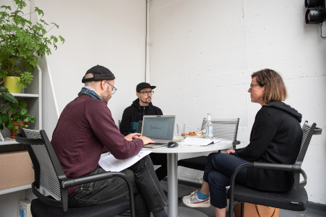 Drei Personen sitzen mit Laptop am Tsich und führen ein Beratungsgespräch