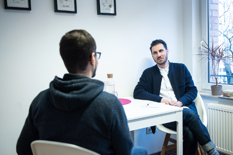 Zwei Männer sitzen sich an einem Tisch im Gespräch gegenüber