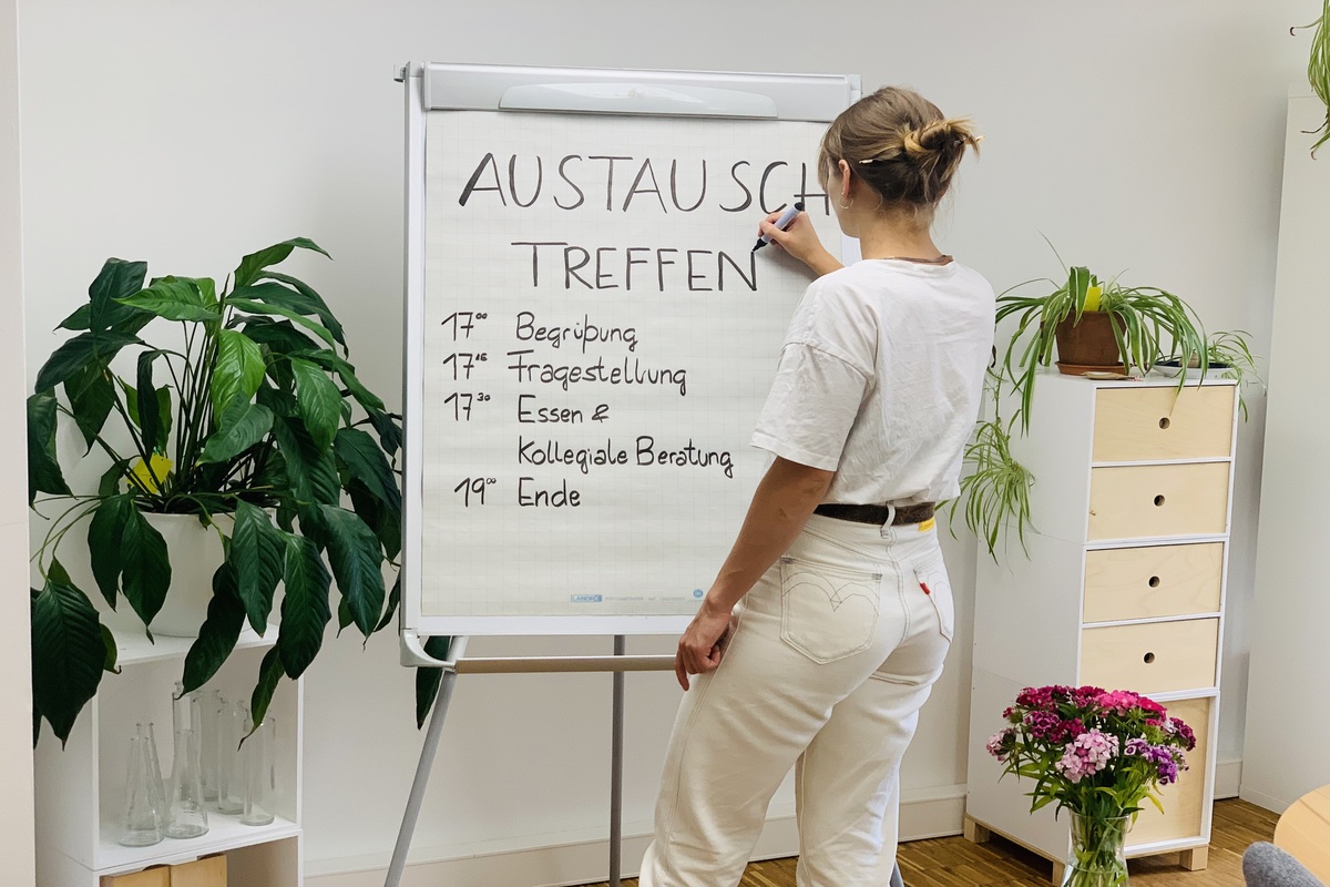 Eine Frau schreibt eine Tagesordnung auf eine Flipchart.