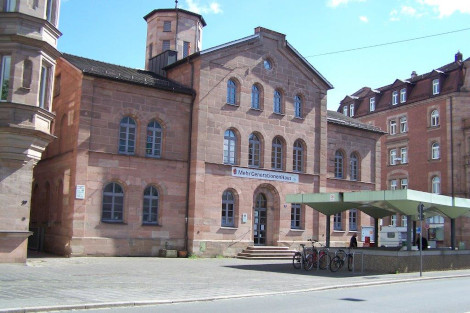 Ein großes Sandsteingebäude mit Bögenfenstern und kleinem Türmchen.