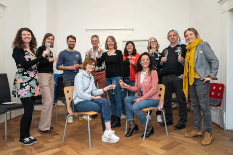 Gruppenfoto von zehn Personen mit Sektgläsen in der Hand.