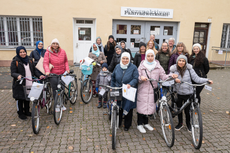 Viele Frauen stehen mit Fahrrädern zusammen.