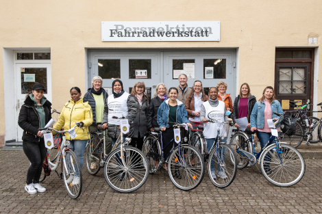 Eine Gruppe von Frauen und ein Mann stehen mit Fahrrädern vor der Fahrradwerkstatt