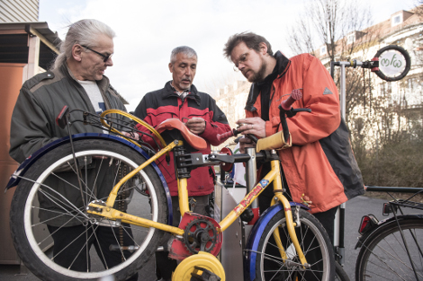 Drei Reparateure arbeiten an einem Fahrrad