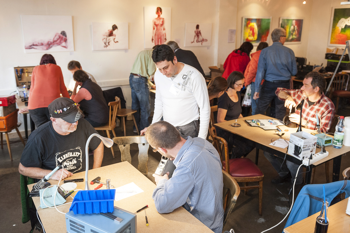 Freiwillige mit Besuchern im Repair Cafe