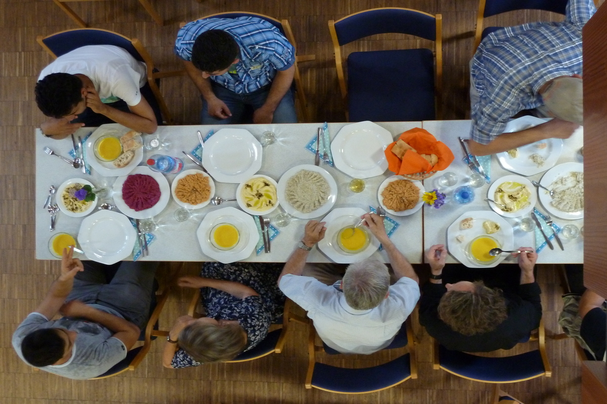 Personen sitzen am Tisch und essen gemeinsam