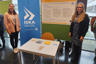 wei Frauen stehen vor einem Roll Up und einem ISAK Poster