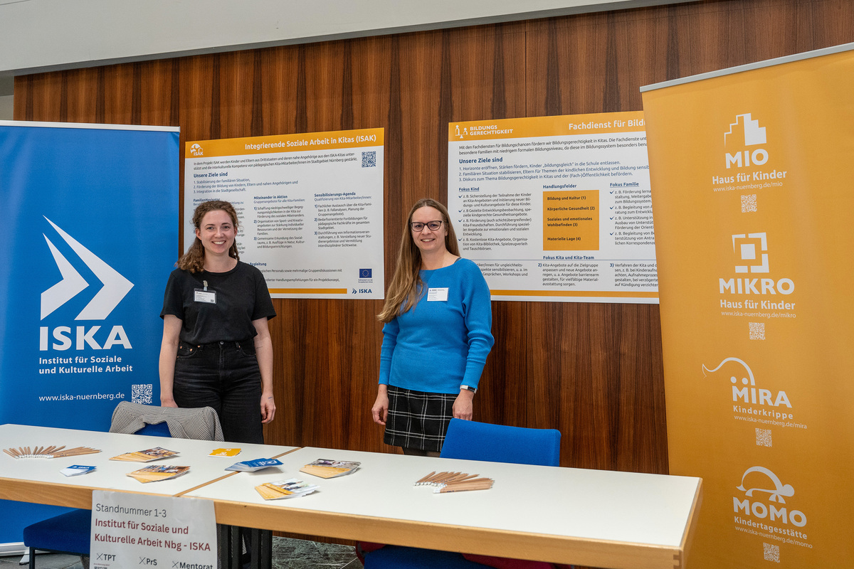 Zwei Projektmitarbeiterinnen stehen am Stand der Fachdienste beim Praxismarkt der TH Nürnberg.