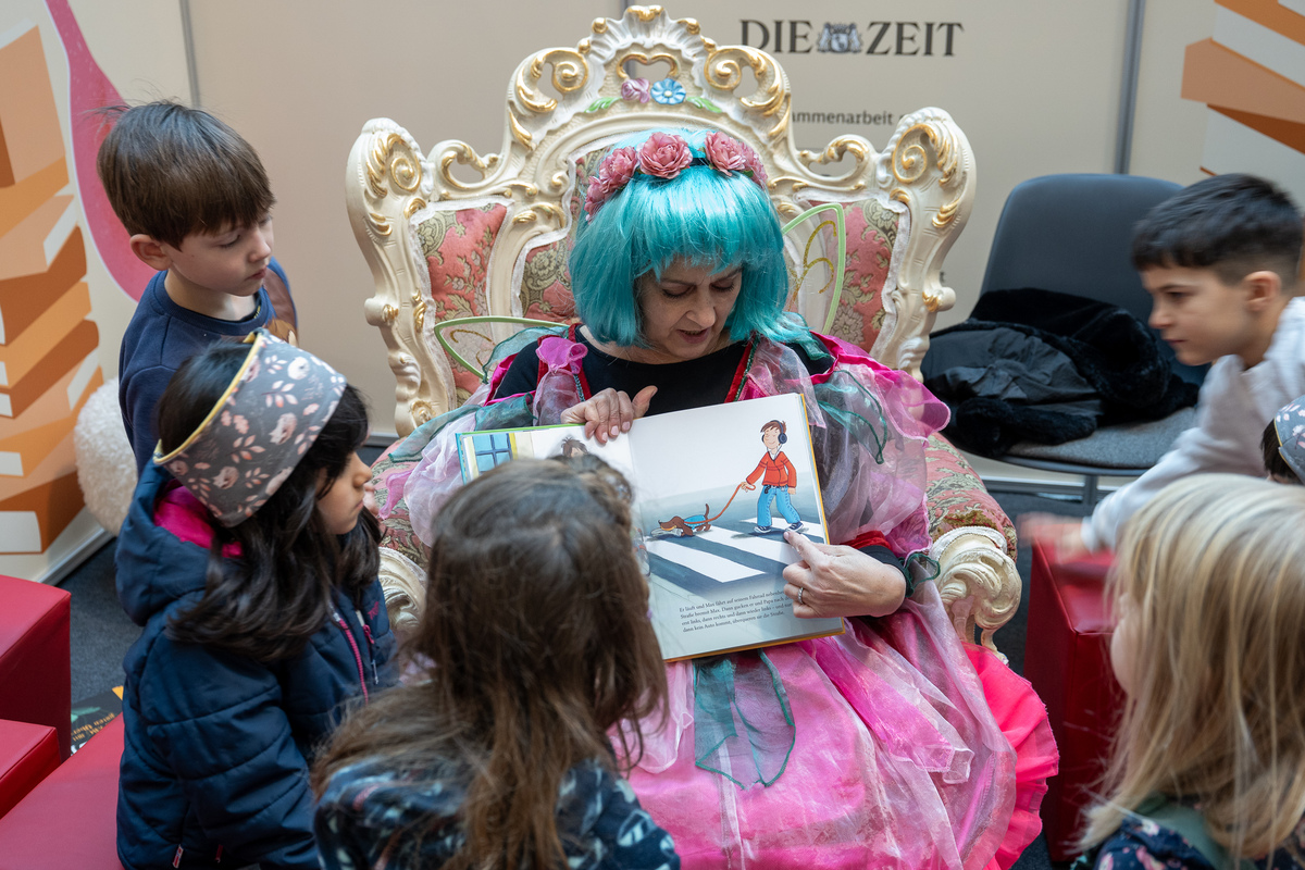 Eine als Fee verkleidete Frau liest einer Gruppe von Kindern vor.