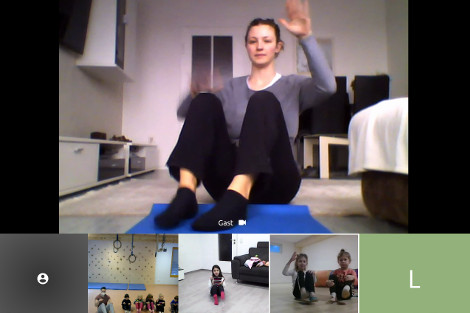 Ein Screenshot zeigt mehrere Teilnehmer/innen eines Videochats: Eine Frau auf einer Yogamatte und mehrere Kinder in einer Turnhalle und in Wohnzimmern.