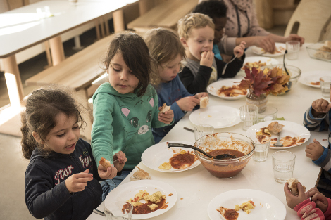 Kinder sitzen beim Essen um den Tisch