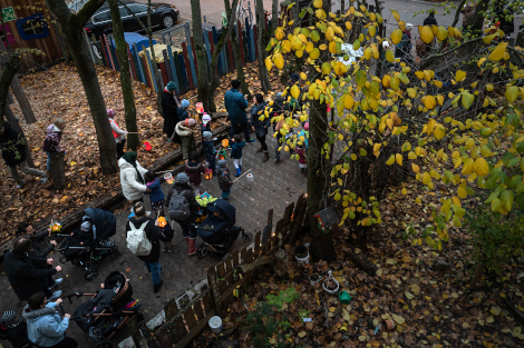 Kinder und Erwachsene laufen mit Laternen über einen Weg.