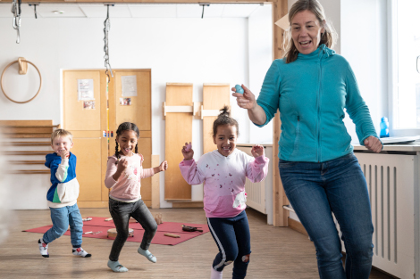 Eine Frau und drei Kinder rennen durch den Raum.