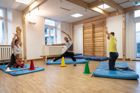 Mehrere Personen machen auf Yogamatten Dehnübungen