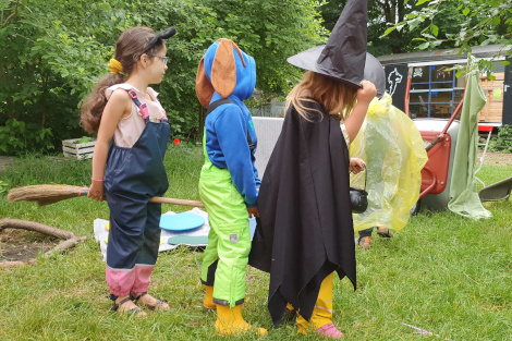 Drei Kinder in Verkleidung von Hexe und Tieren sitzen auf einem Besen