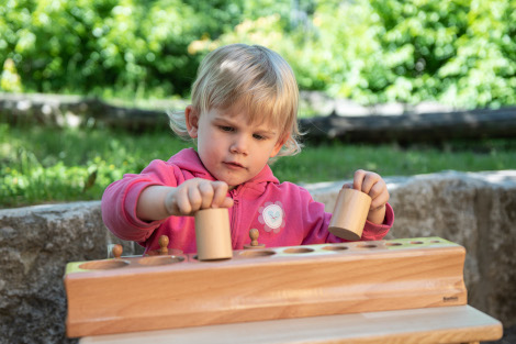 Ein Kind sortiert Holzzylinder nach Größe und Gewicht