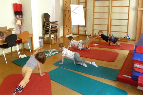 Vier Kinder machen eine Yogaübung im Vierfüßlerstand auf Turnmatten