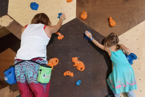 Eine Frau und ein Mädchen klettern an einer Boulderwand