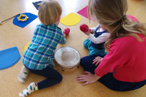 Kinder spielen am Boden mit verschiedenen Instrumenten