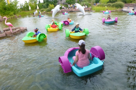 Kinder sitzen in kleinen bunten Booten, die auf einem See schwimmen.