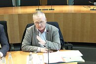 Ein älterer Mann sitzt auf einem Rang im Sitzungssaal des Deutschen Bundestages und redet in ein Mikro.