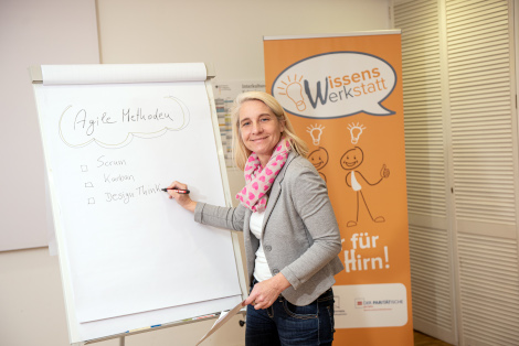 eine Frau steht vor einem Flipchart und schreibt Stichpunkte zum Thema agile Methoden aud