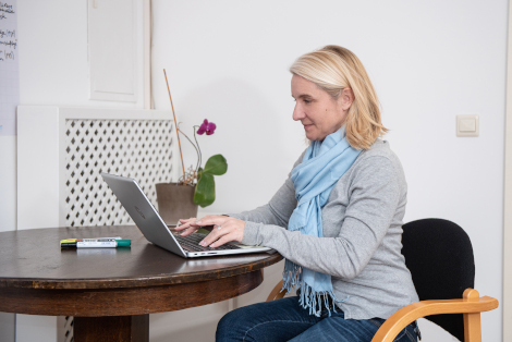 es sitzt eine Frau am Schreibtisch und schreibt etwas auf ihrem Laptop