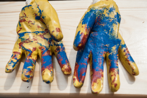 gelbe Arbeitshandschule mit blauen und roten Flecken au einem Tisch