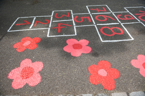ein mit weisser Kreide auf die Strasse gemaltes Hüpffeld mit roten Zahlen von 1 bis 10