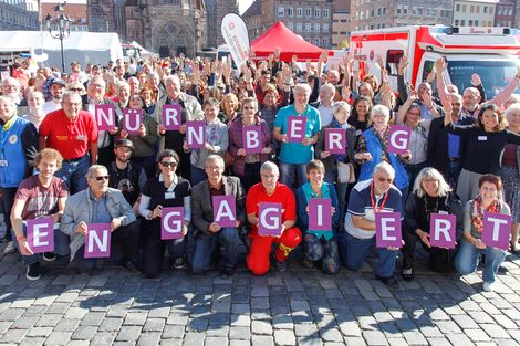 Freiwillige auf dem Nürnberger Hauptmarkt halten Schilder zum Thema Ehrenamt in der Hand