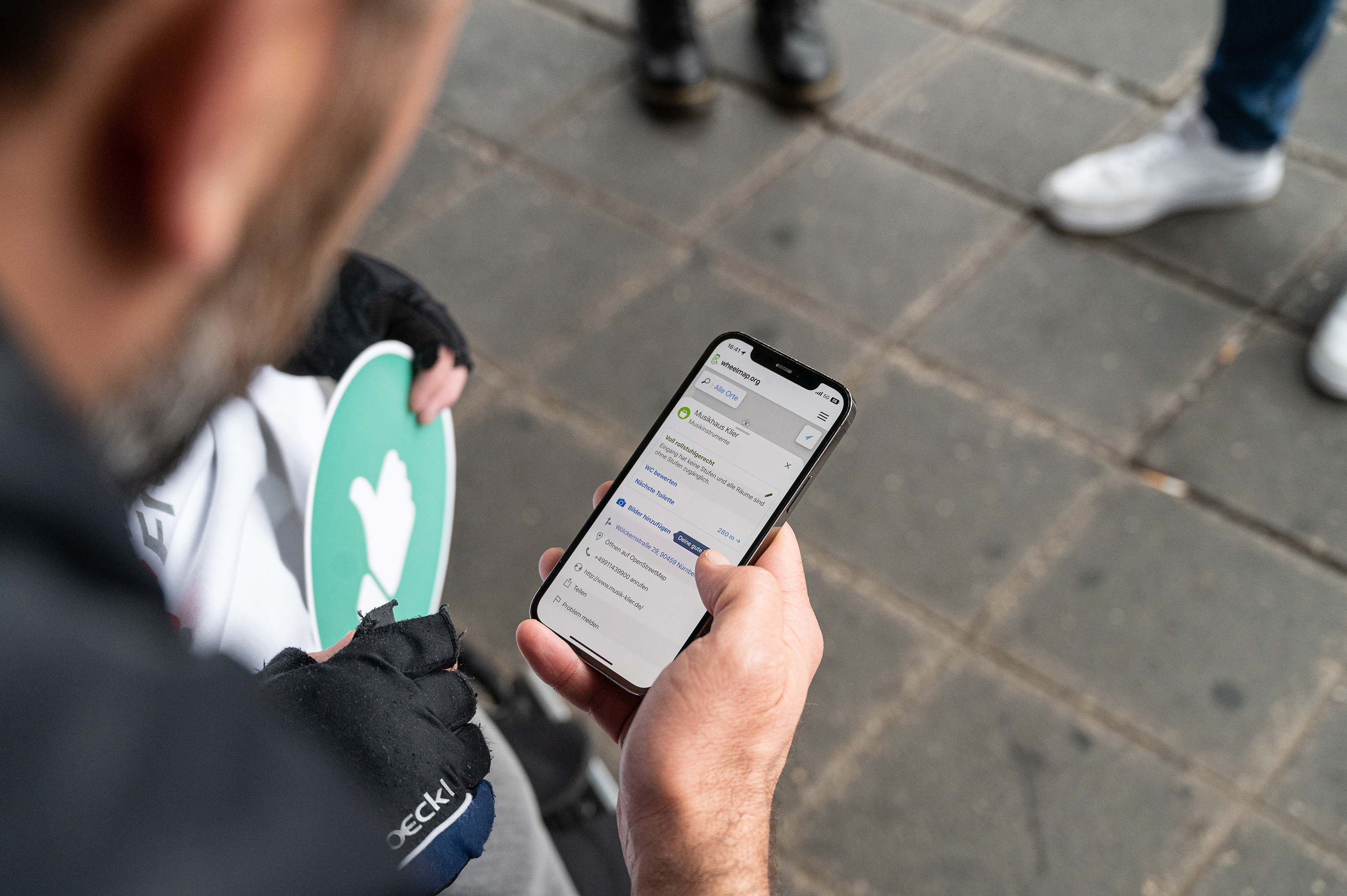 Ein Freiwilligerbedient die App Wheelmap auf seinem Mobiltelefon