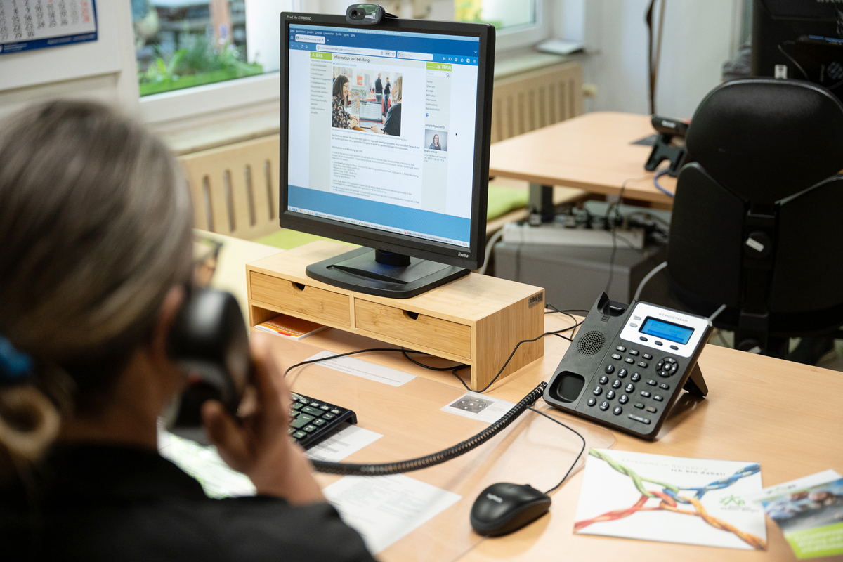 Eine Mitarbeiterin sitzt vor dem PC und telefiniert