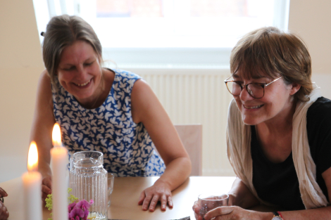 Zwei Frauen im Gespräch an einem Tisch mit zwei Kerzen