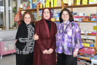 3 Sprachvermittlerinnen stehen vor einem Regal mit Spielzeug